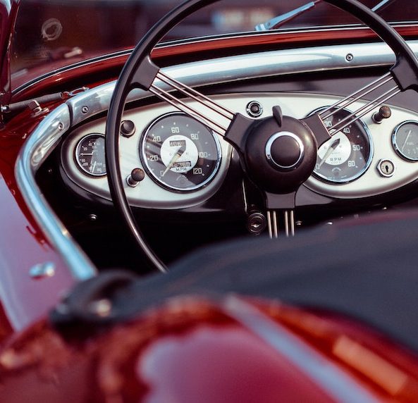 Black steering wheel and dashboard of vintage red car