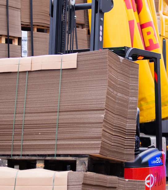 Flat cardboard boxes stacked onto a pallet on a forklift truck