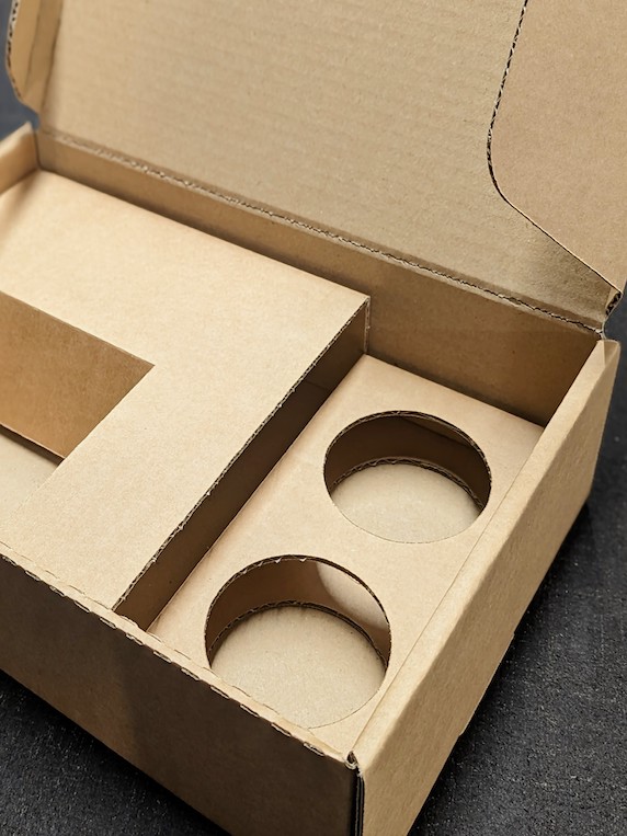 Corrugated cardboard box with bespoke fittings cut out to properly fit required product
