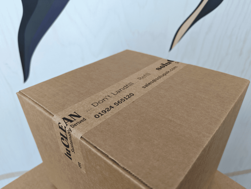 Closed corrugated cardboard box with branded kraft paper tap stating 'soluCLEAN' in black text sealing two flaps