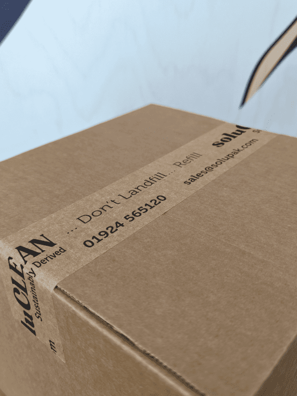 Closed corrugated cardboard box with branded kraft paper tap stating 'soluCLEAN' in black text sealing two flaps