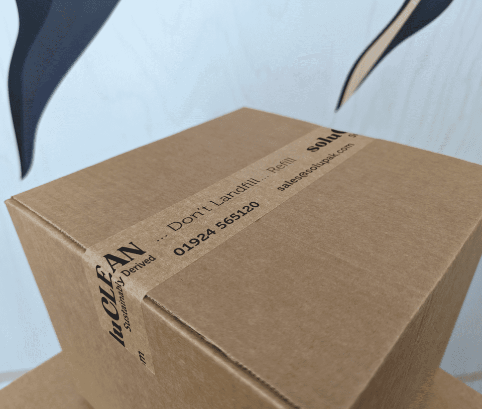 Closed corrugated cardboard box with branded kraft paper tap stating 'soluCLEAN' in black text sealing two flaps