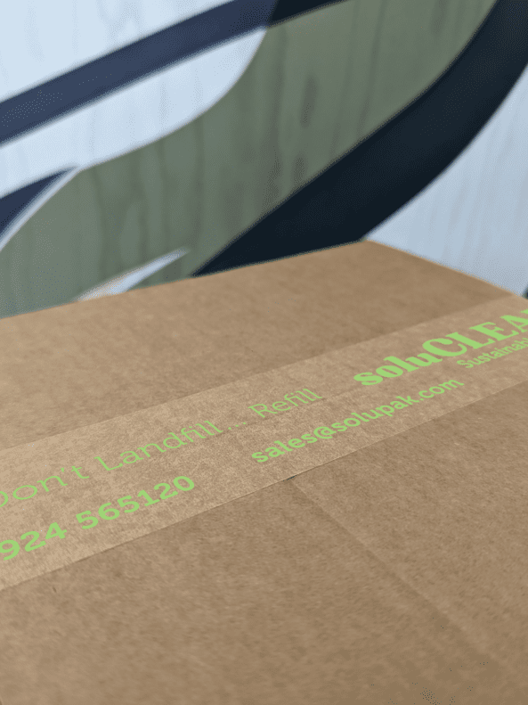 Closed corrugated cardboard box with branded kraft paper tap stating 'soluCLEAN' in green text sealing two flaps