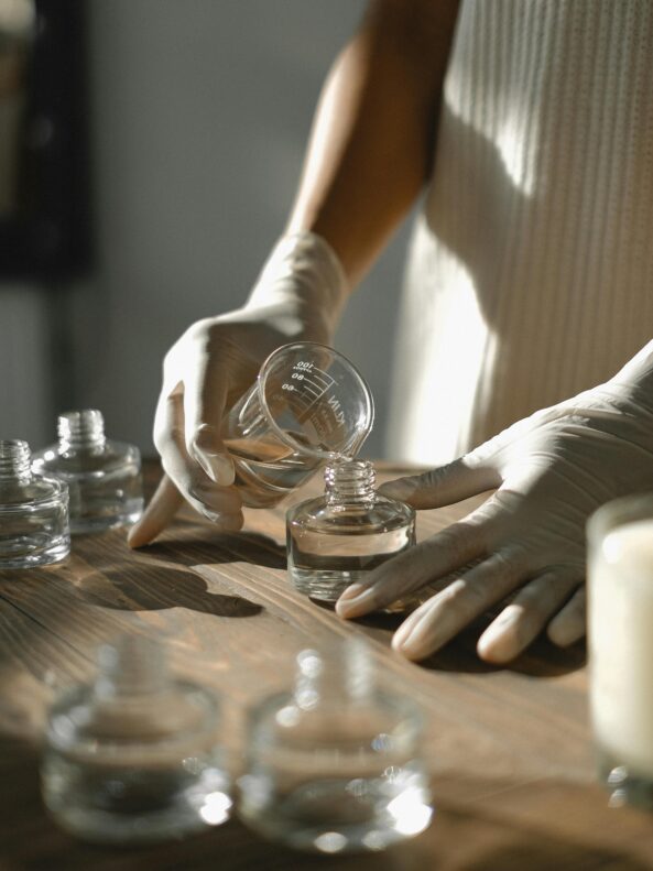 Person pouring a chemical from a glass beaker into a glass container